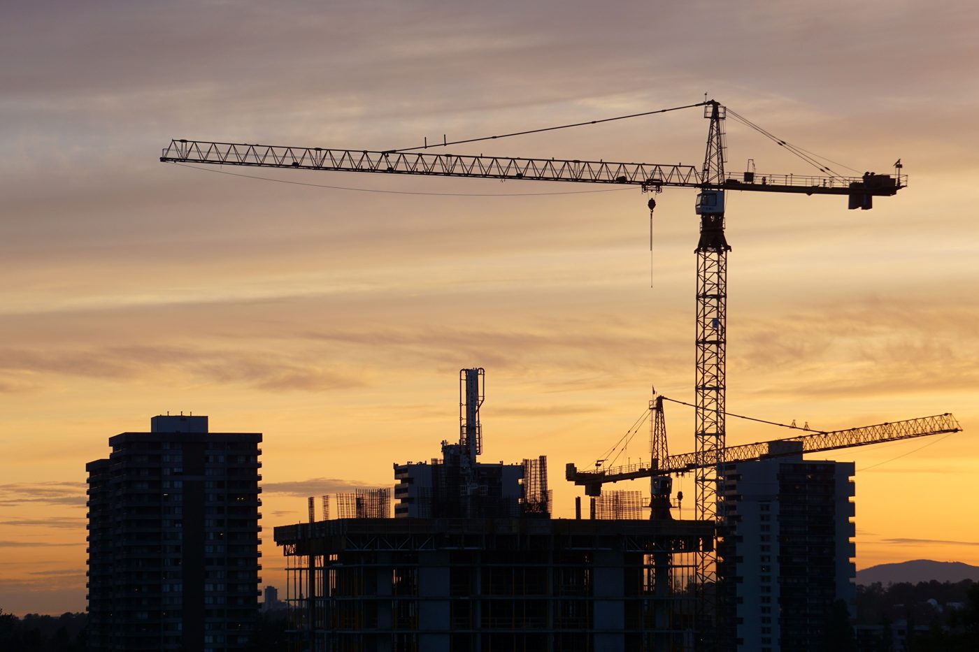 Construction cranes over a building under construction at dusk